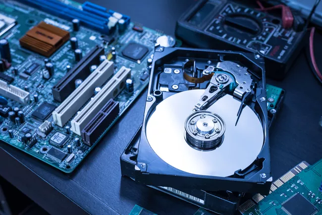 The abstract image of inside of hard disk drive on the technician's desk and a computer motherboard as a component. the concept of data, hardware, and information technology.